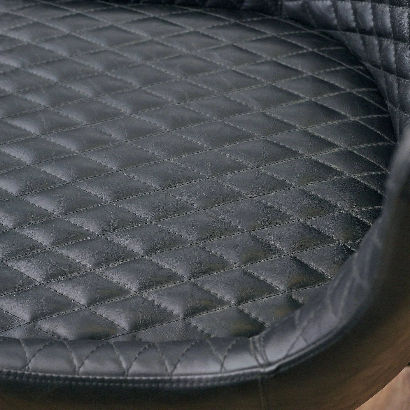 Black faux leather office chair seat with diamond quilted stitching detail close-up