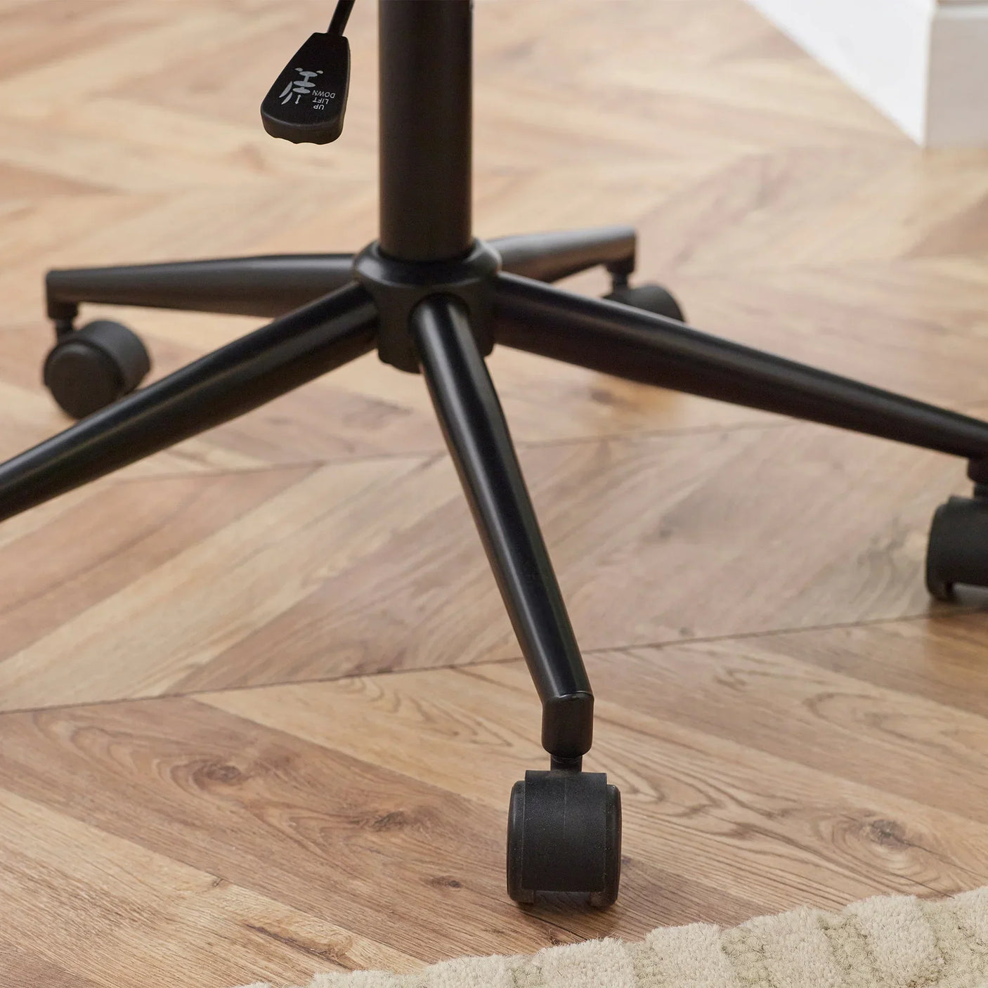 Office chair base with black metal legs and caster wheels on wooden floor