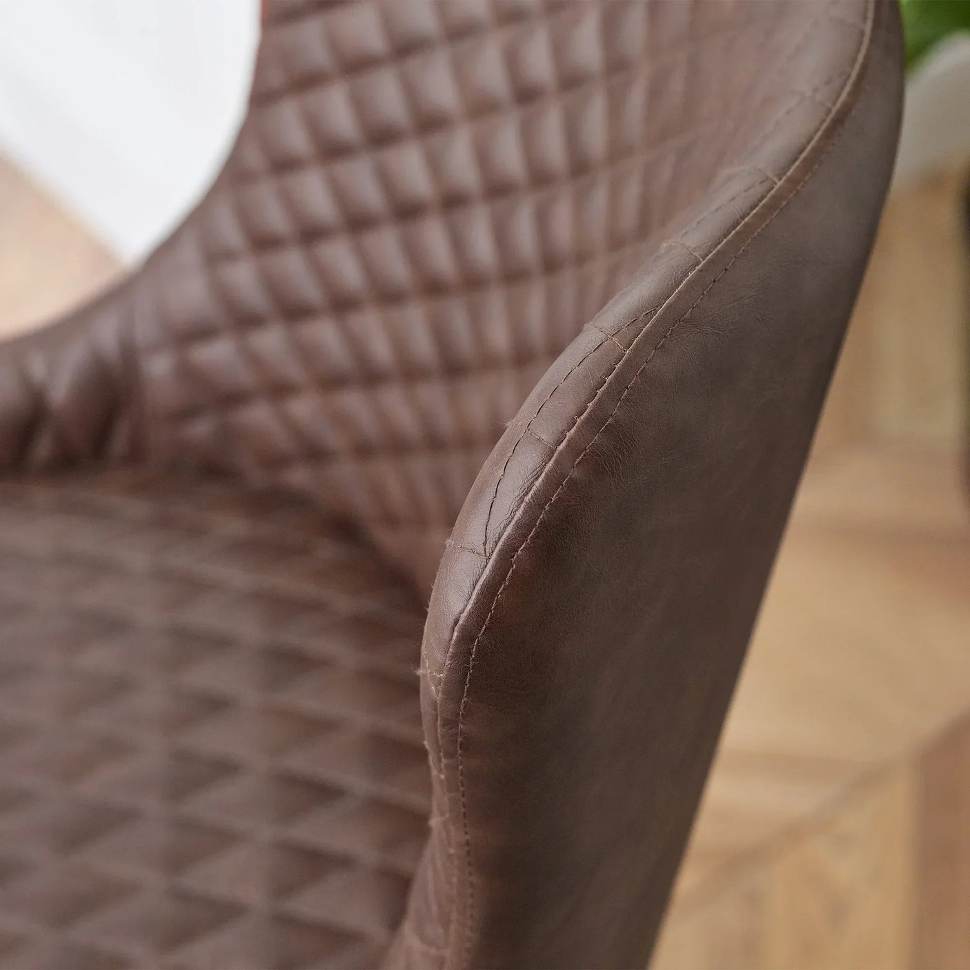 Close-up of brown faux leather office chair with quilted stitching on seat and backrest