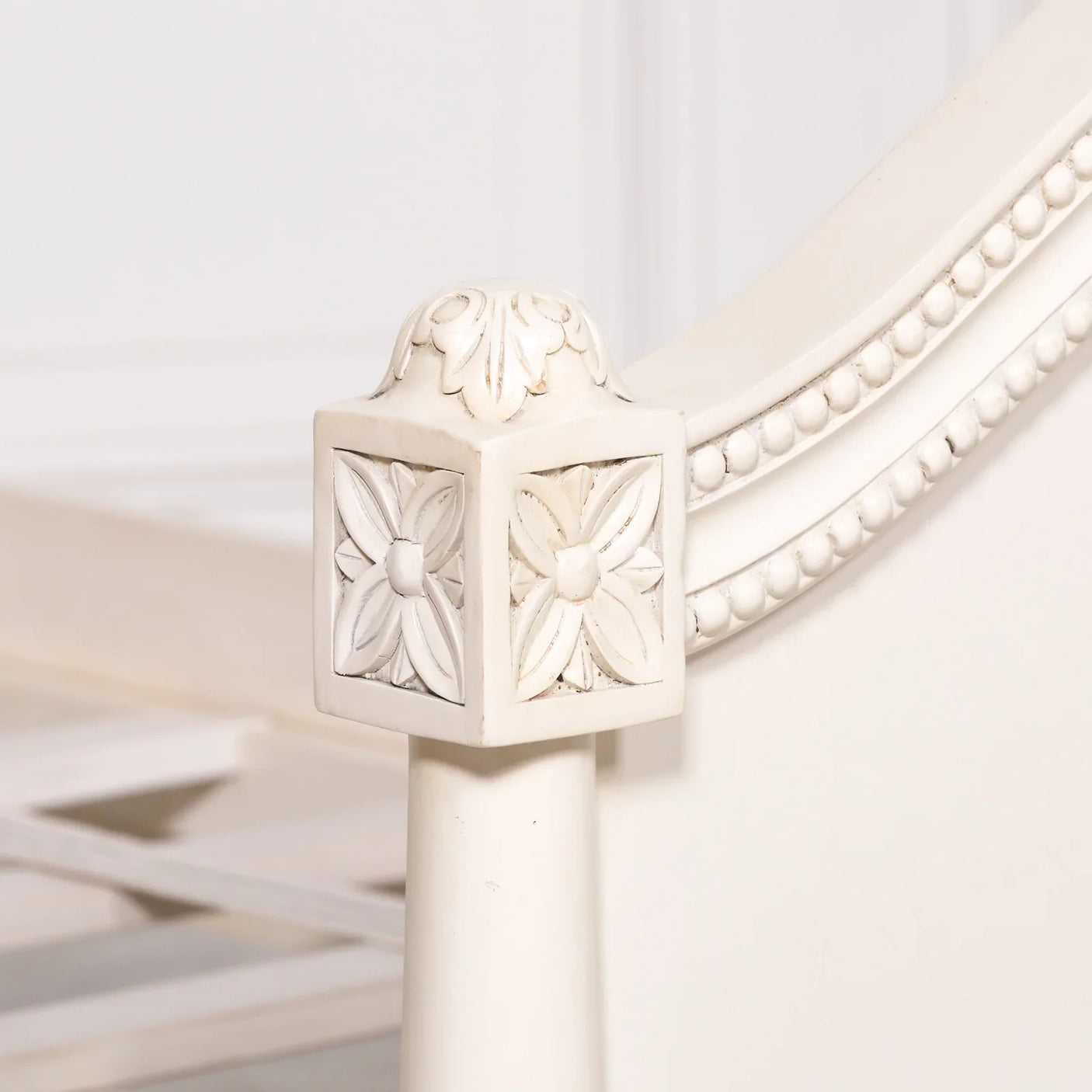 Close-up of carved white wooden bed corner with floral details
