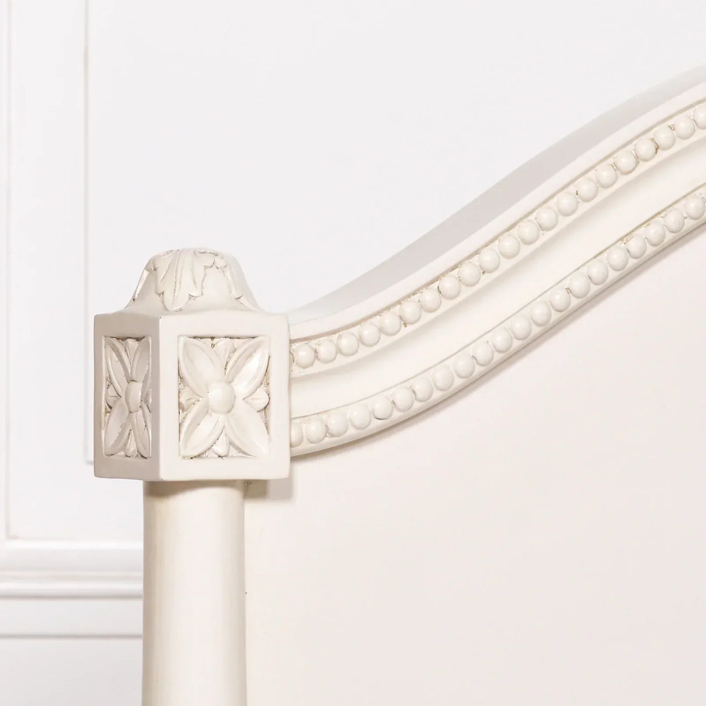Ivory wood bed frame with carved floral detail and beaded trim on headboard
