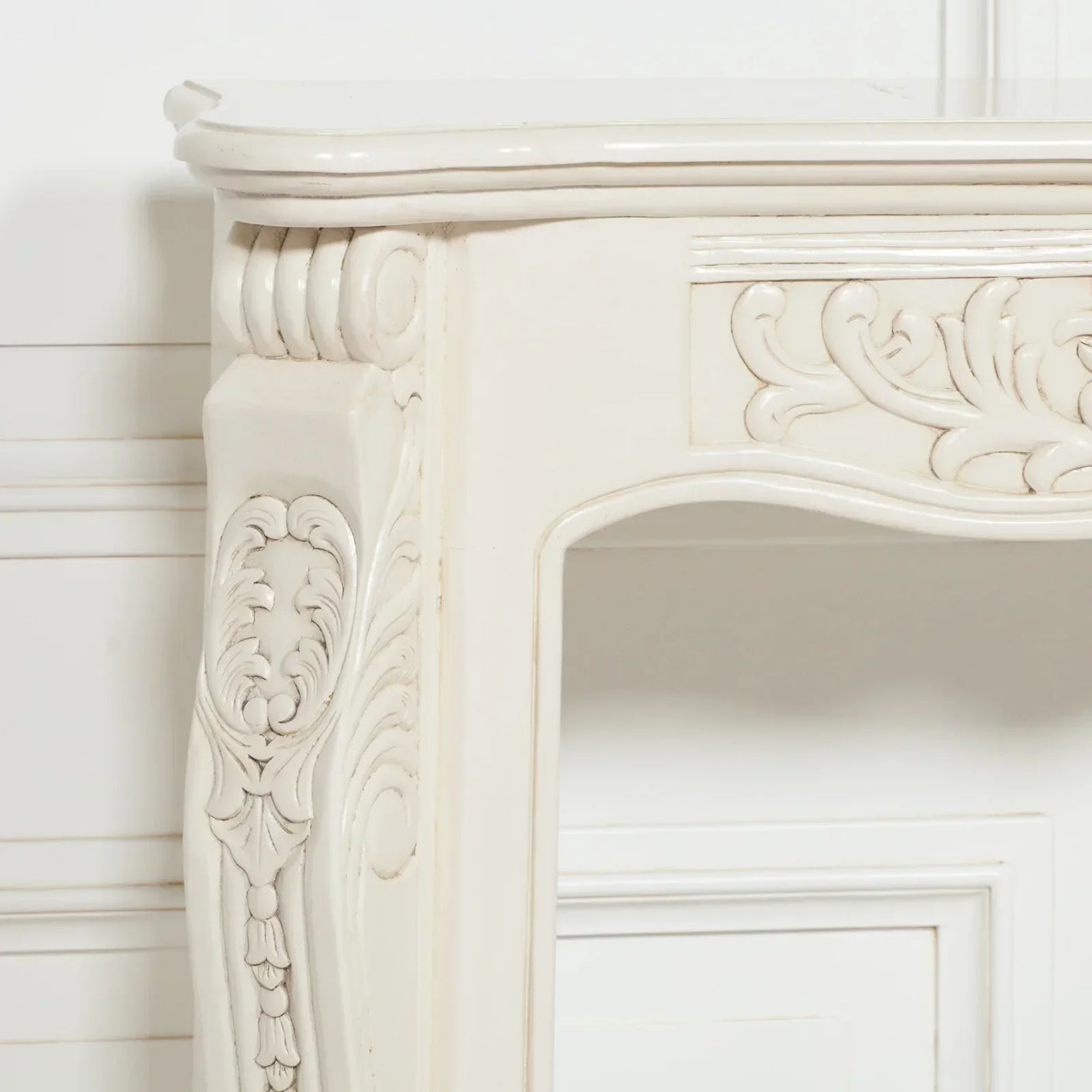 Ivory wooden fireplace surround with ornate carved detailing in close-up view