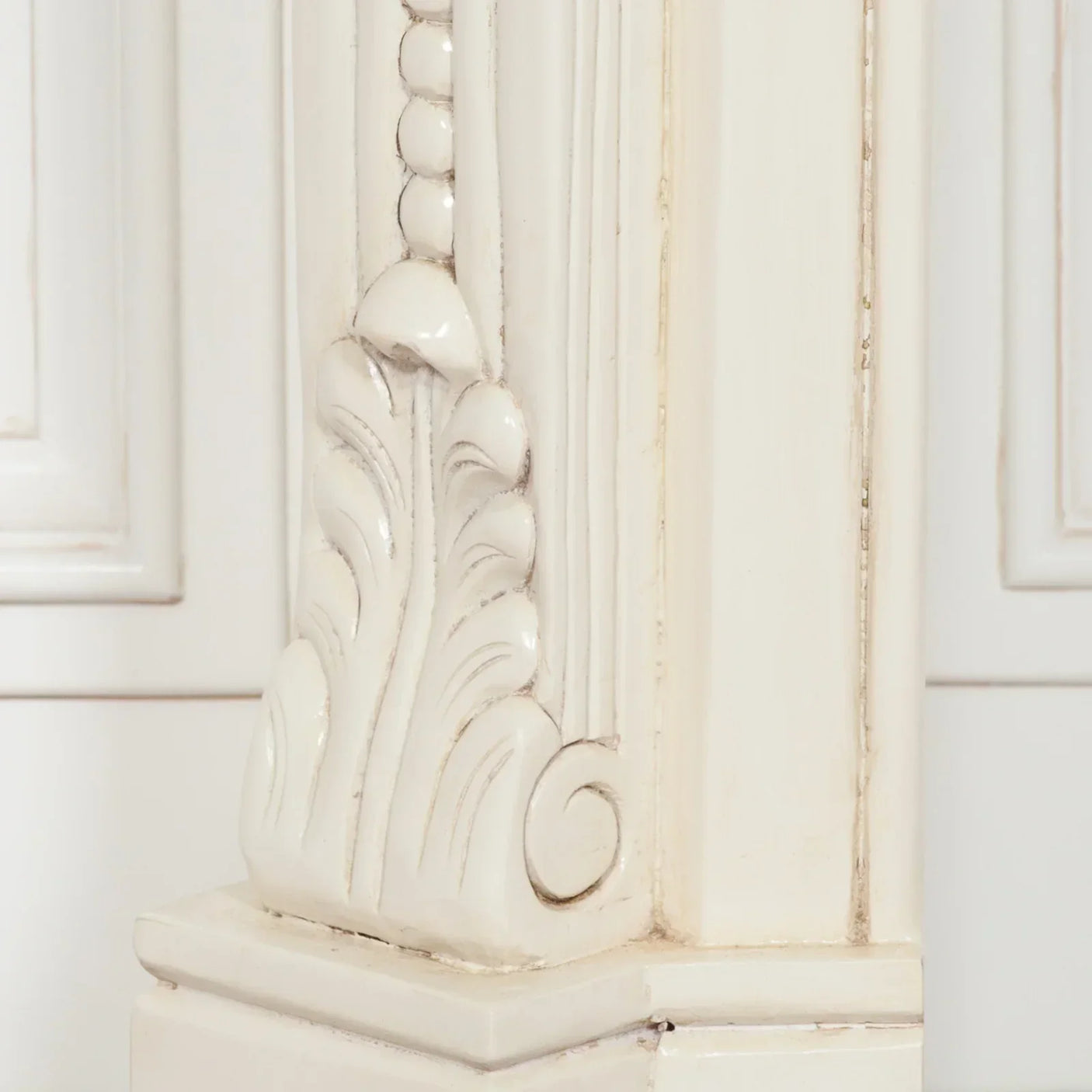 Close-up of carved wood furniture leg with cream finish and ornate detailing