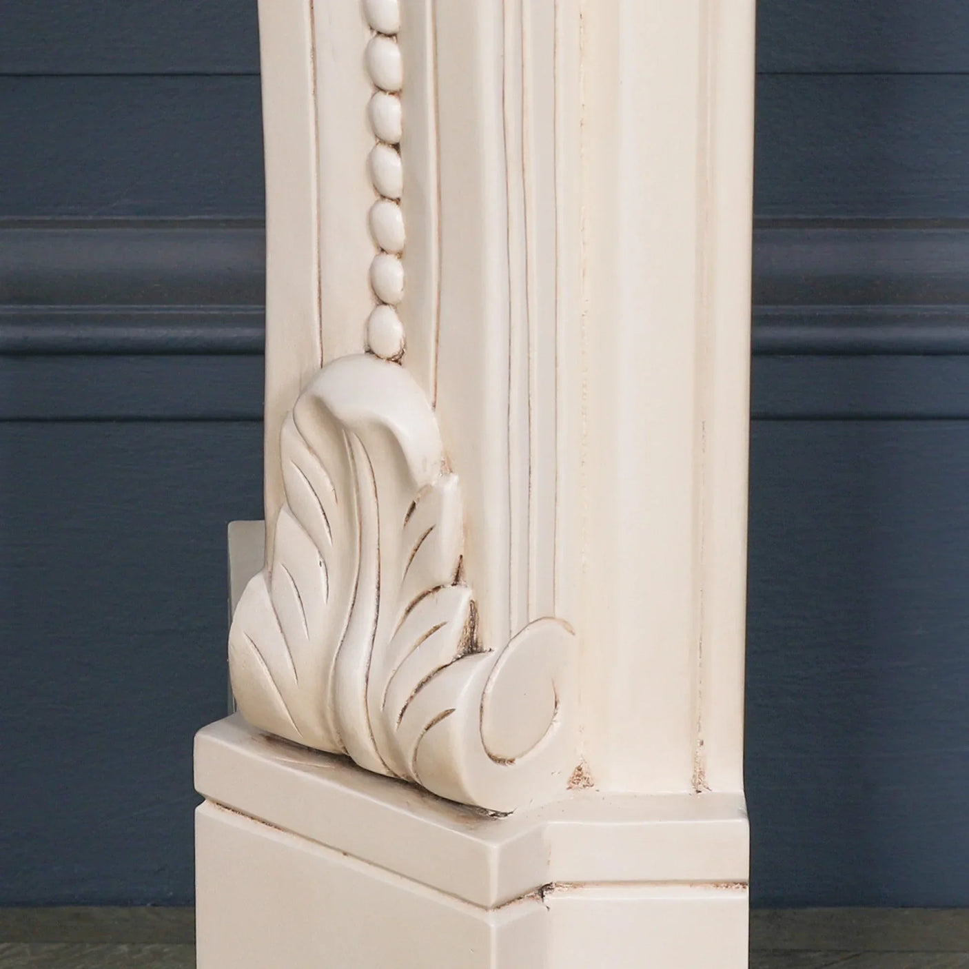 Cream painted fireplace surround with carved wood detail and beaded trim