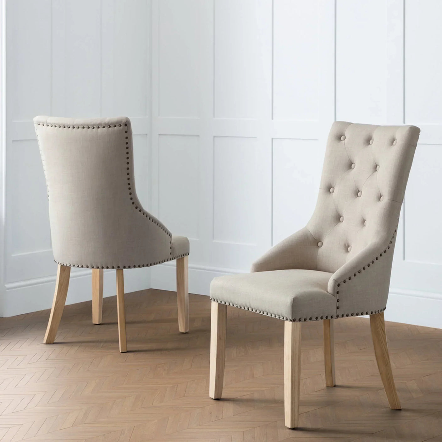 Beige button back dining chair with stud detail and oak legs in modern room