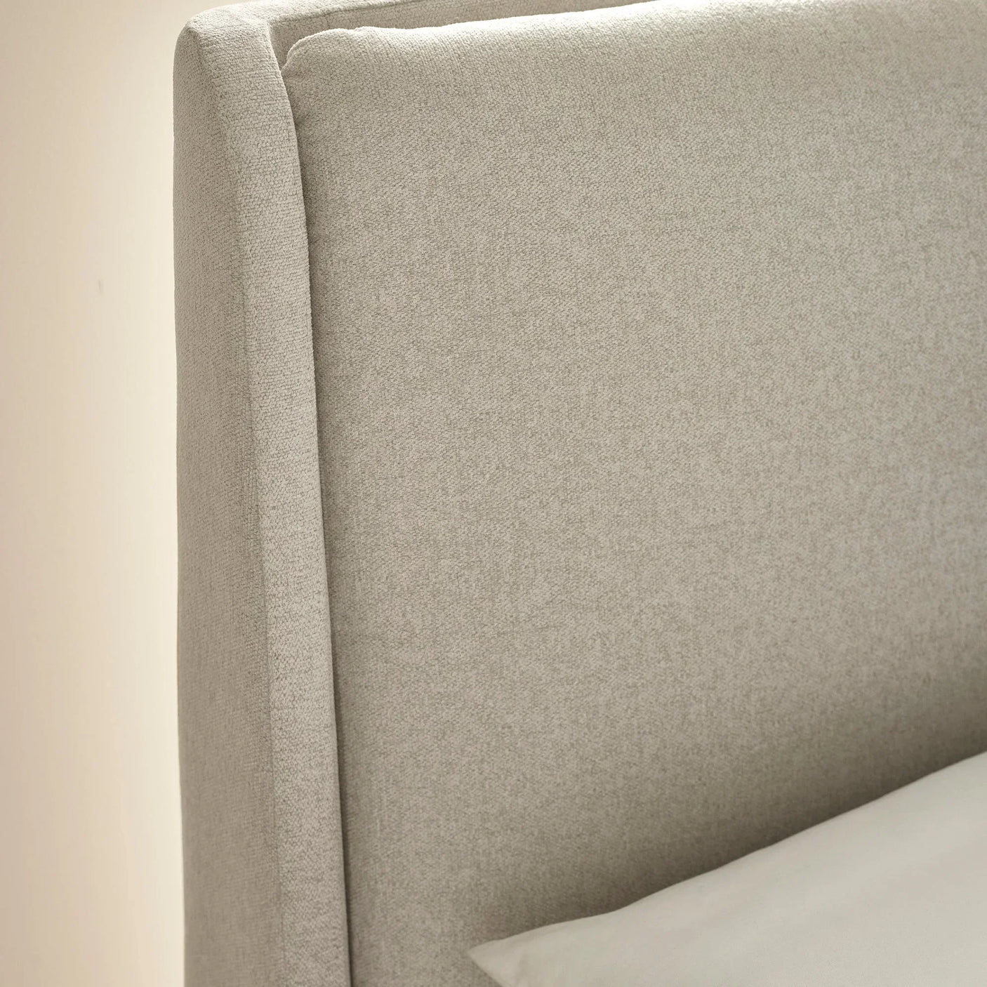 Light grey upholstered bed headboard with textured fabric and clean straight edges