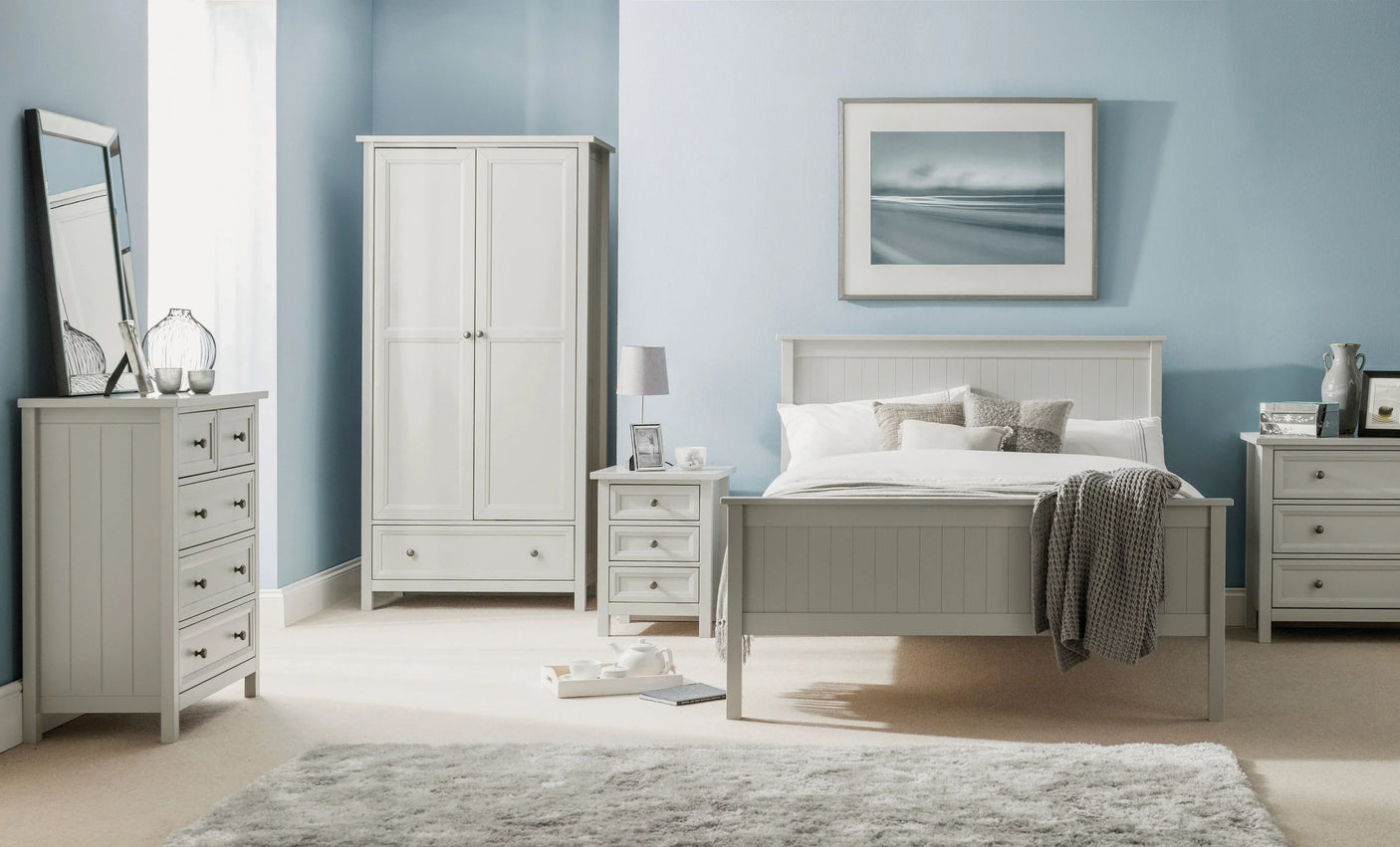 Maine three drawer bedside table in dove grey beside matching wardrobe and bed in bedroom set