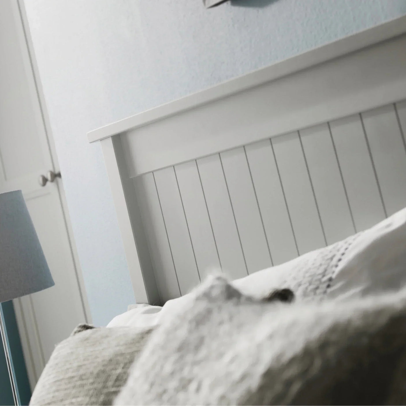 Panelled grey bed headboard with textured bedding in a bright bedroom