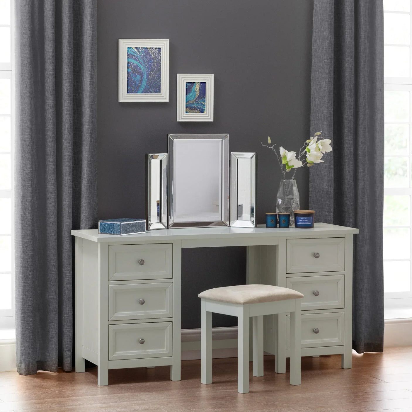 White dressing table with six drawers, padded stool, and mirrored vanity in modern room