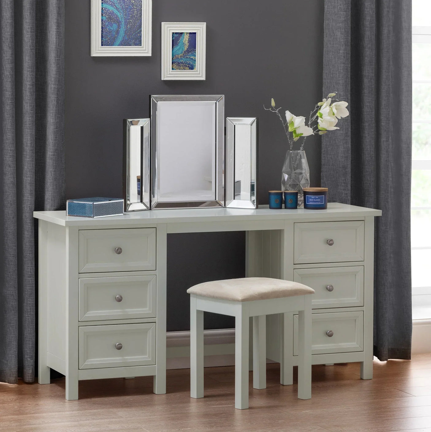 Dove grey dressing stool with padded seat in front of matching vanity table in modern room