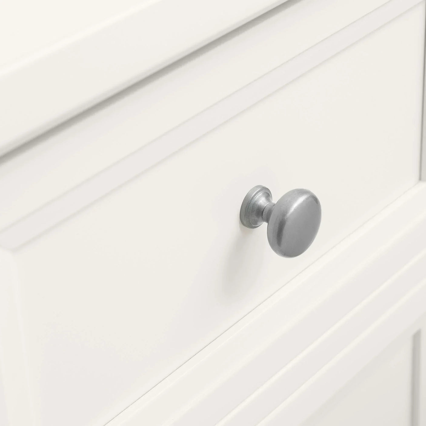 White bedside table drawer with round silver metal handle close-up
