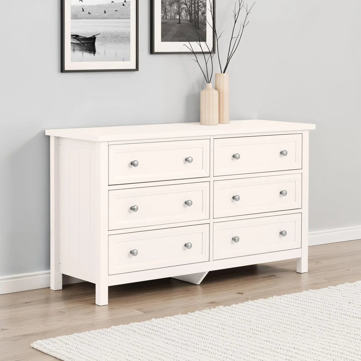 White wooden chest of drawers with six drawers and silver handles in modern bedroom