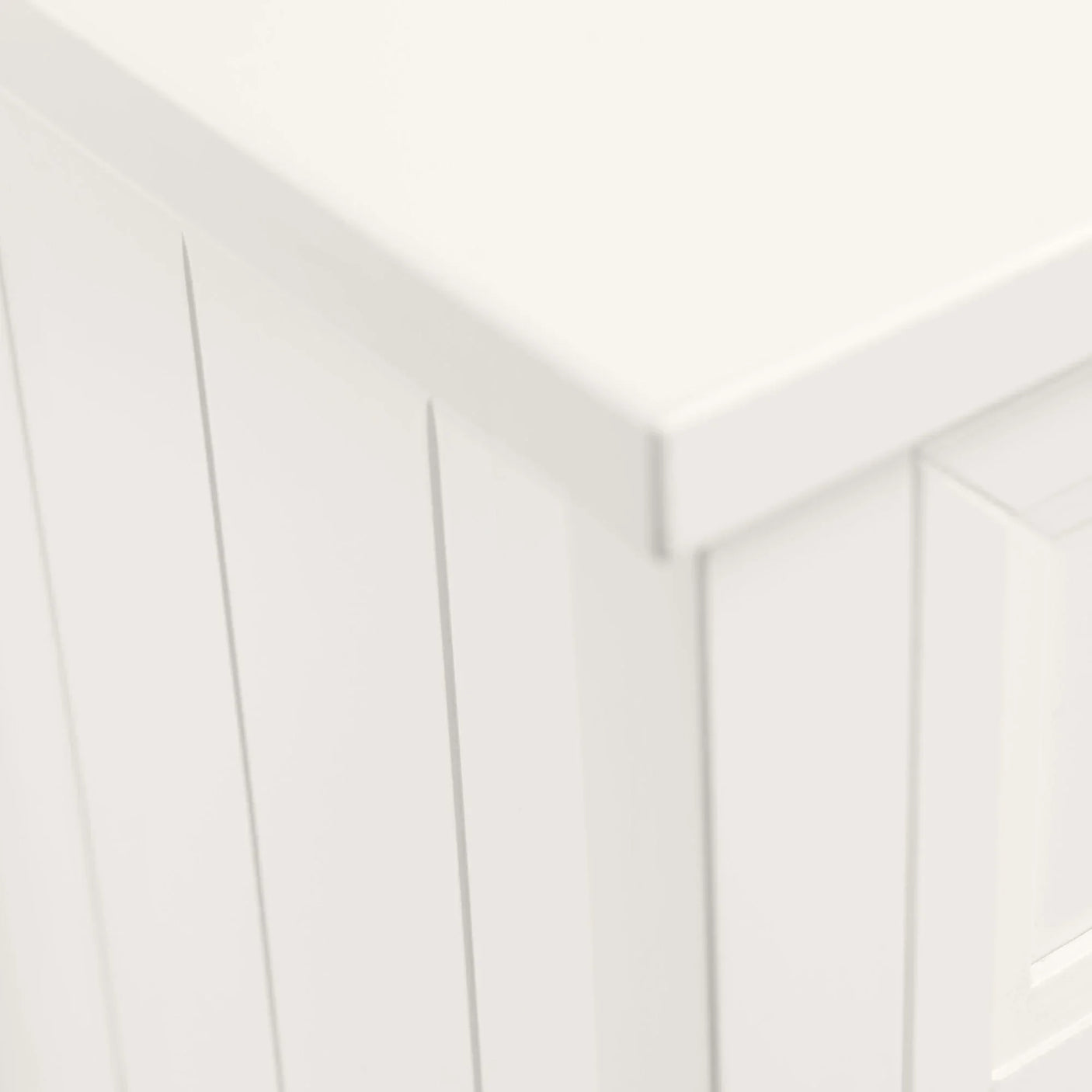 White painted wood cabinet with vertical paneling and smooth top corner detail