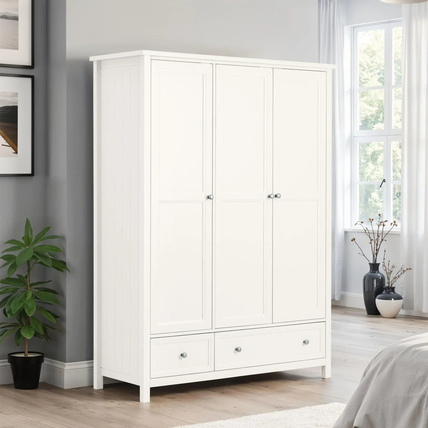 White wooden wardrobe with three doors and two drawers in modern bedroom