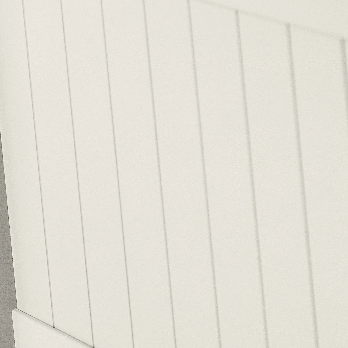 White panelled furniture surface with vertical grooves, close-up of painted wood texture