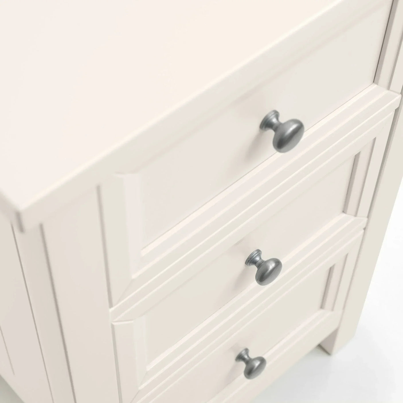 Cream chest of drawers with silver handles, close-up side angle