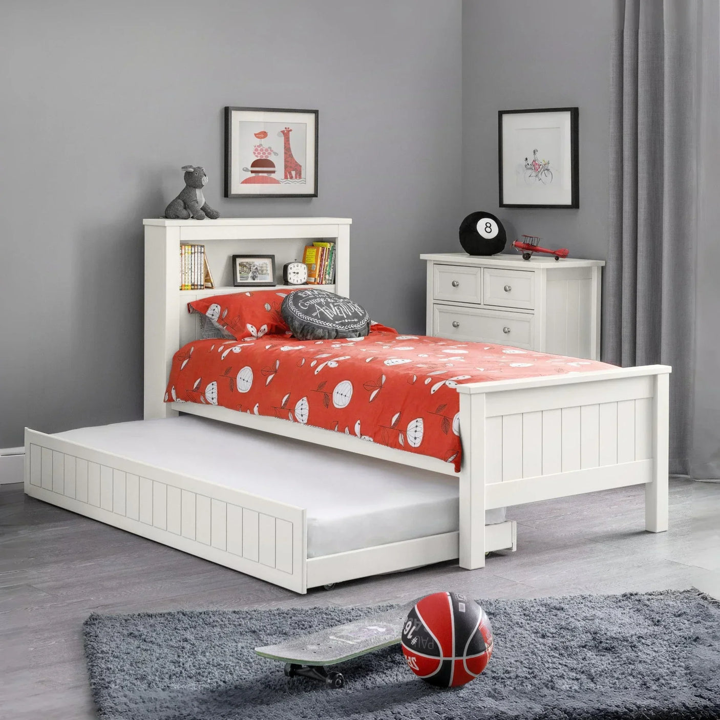 White wooden kids bed with trundle storage, red bedding, headboard shelves, grey decor