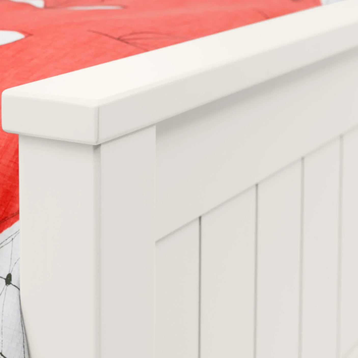 White wooden bed frame close-up showing panel detail with red bedding