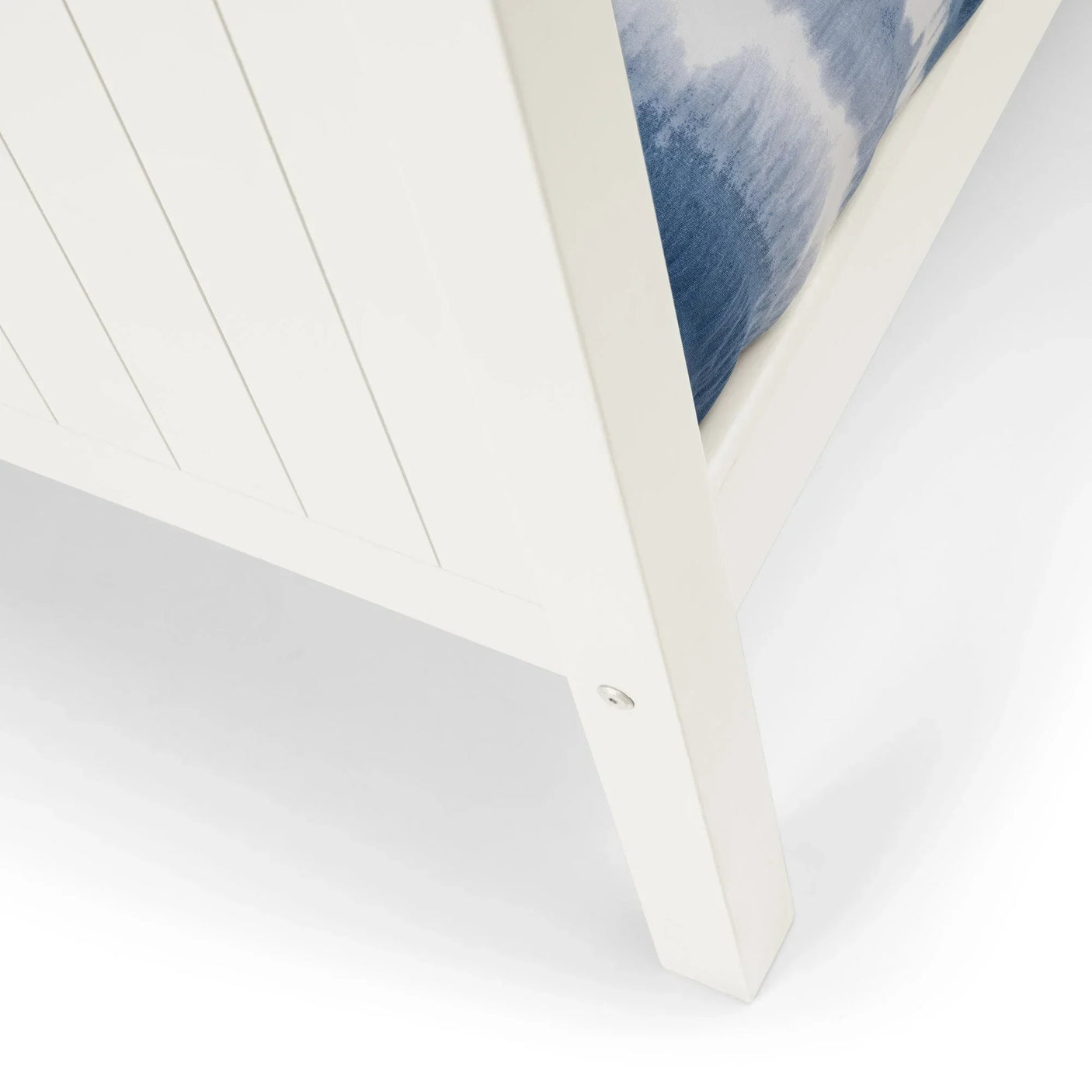 White wooden bed frame corner with panel detailing and blue mattress visible