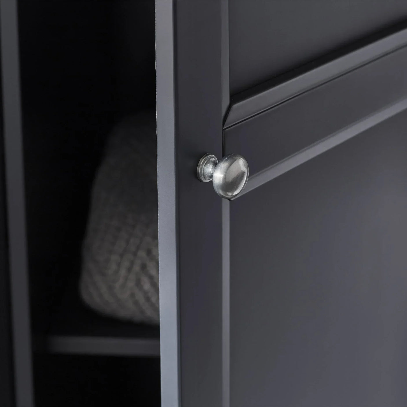 Anthracite wardrobe door closeup with metal knob and visible interior shelf