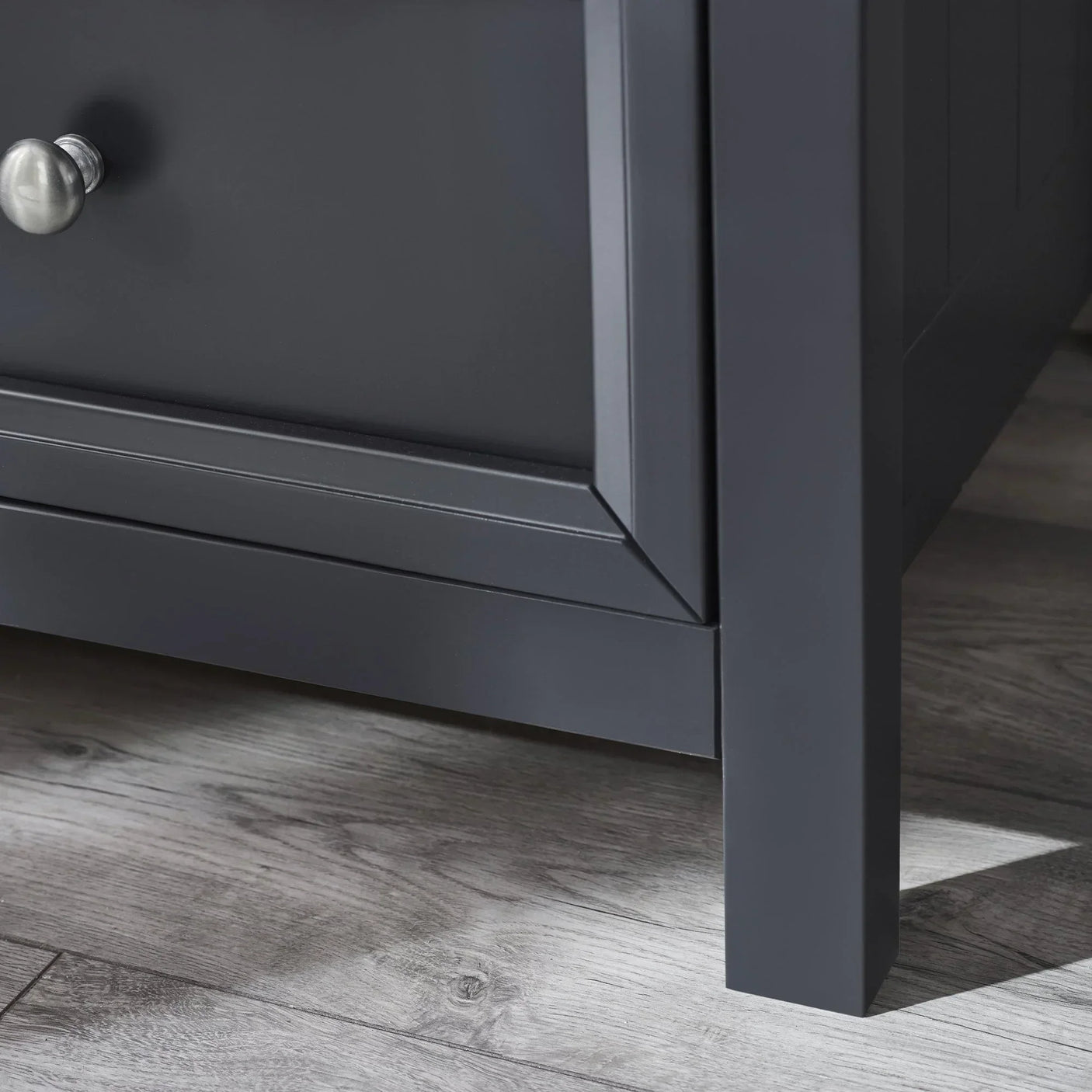 Anthracite wardrobe leg and lower panel detail on wood floor with metal knob