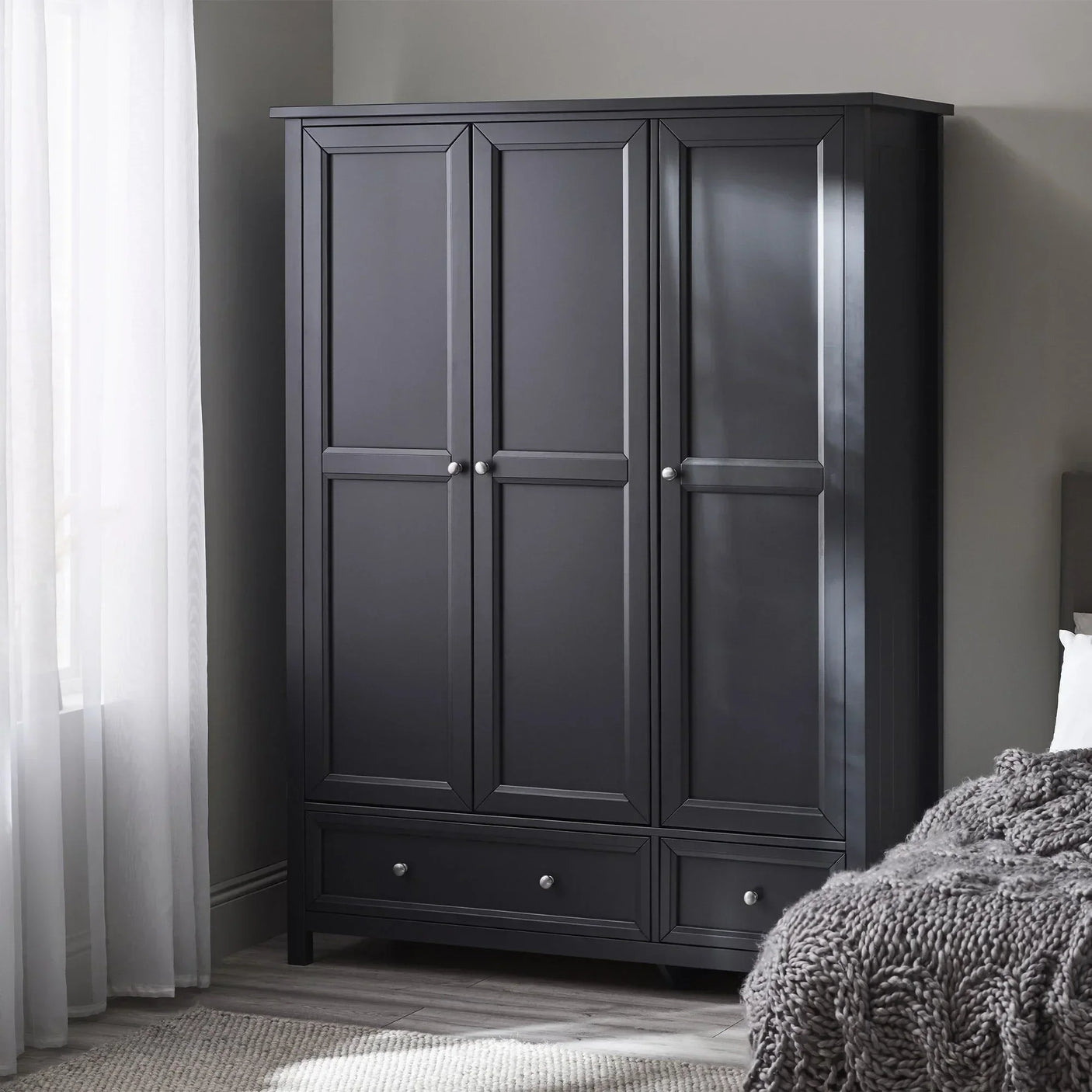 Anthracite three-door wardrobe with two lower drawers in modern bedroom