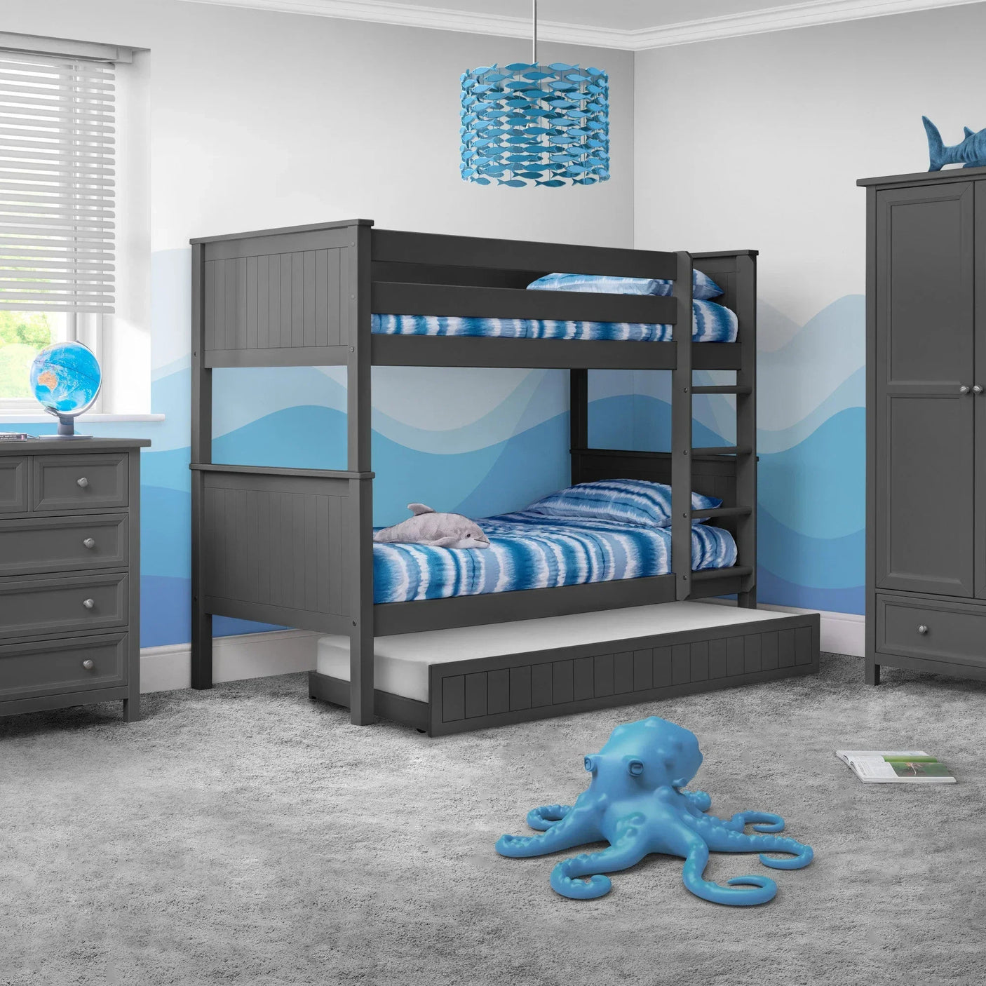 Grey wooden kids bunk bed with trundle, blue bedding, in nautical themed bedroom