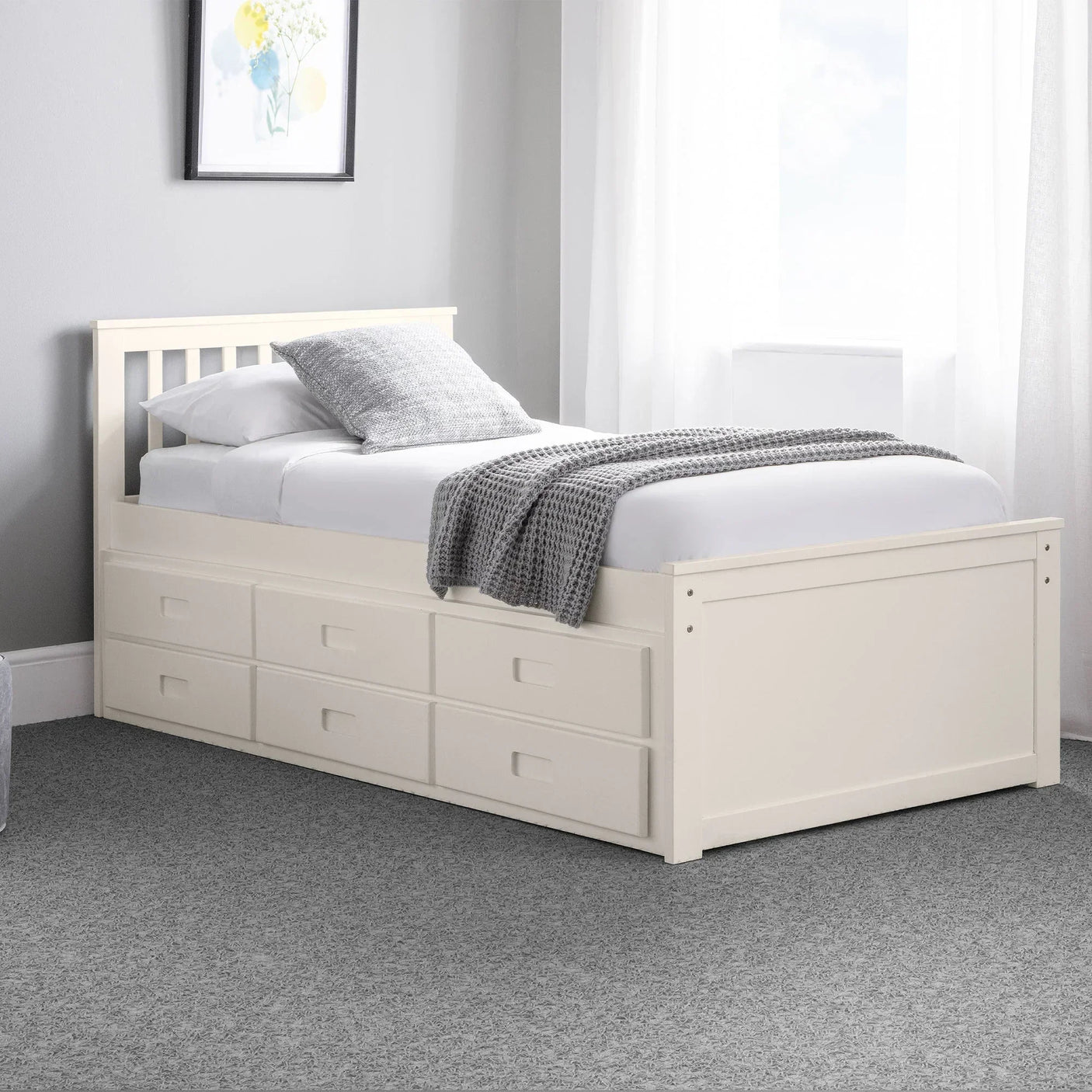 White single daybed with storage drawers, grey blanket, and pillow in bright bedroom