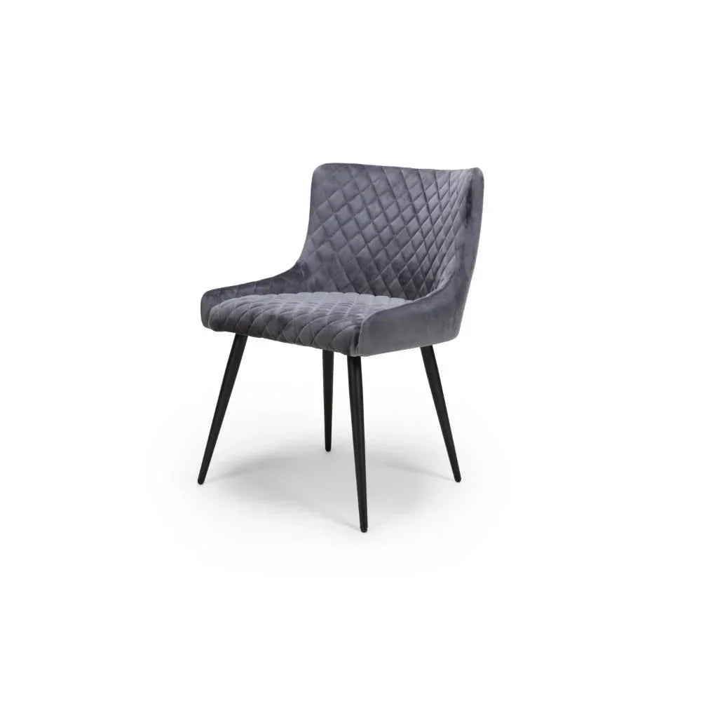 Grey velvet dining chair with diamond stitching and black metal legs, angled front view