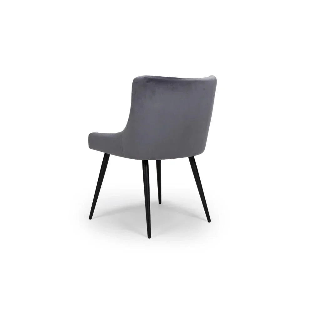 Grey velvet dining chair with curved backrest and black metal legs, rear view