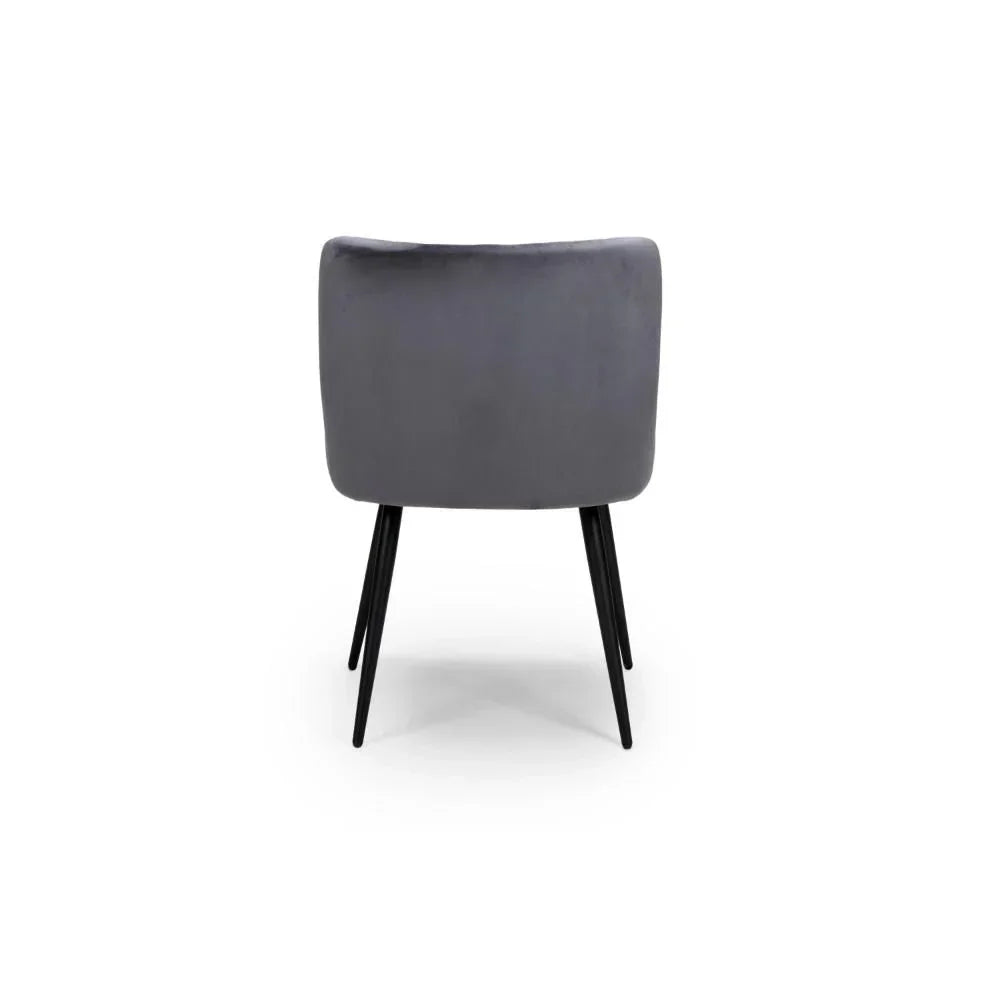 Rear view of grey velvet dining chair with black metal legs on white background