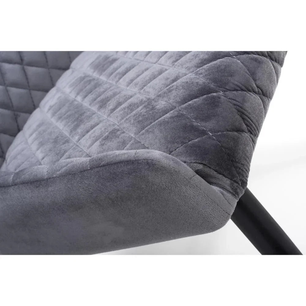 Close-up of grey velvet dining chair with diamond quilted stitching and black metal leg