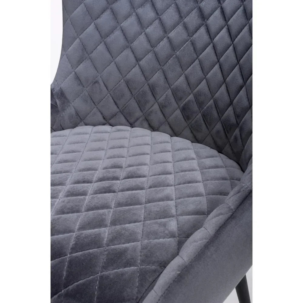 Close-up of grey velvet accent chair with diamond quilted upholstery pattern