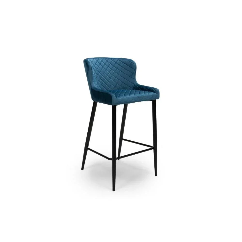 Blue velvet bar stool with quilted backrest and black metal legs on white background