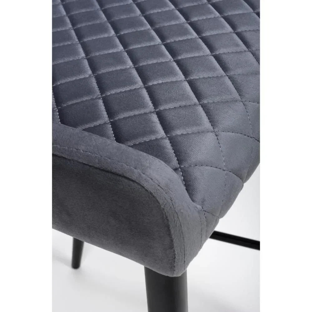 Grey velvet dining chair seat with quilted stitching and black metal legs close-up
