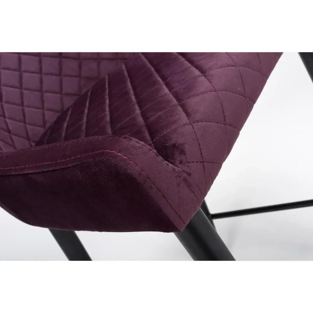 Close-up of purple velvet dining chair seat with quilted stitching and black metal legs