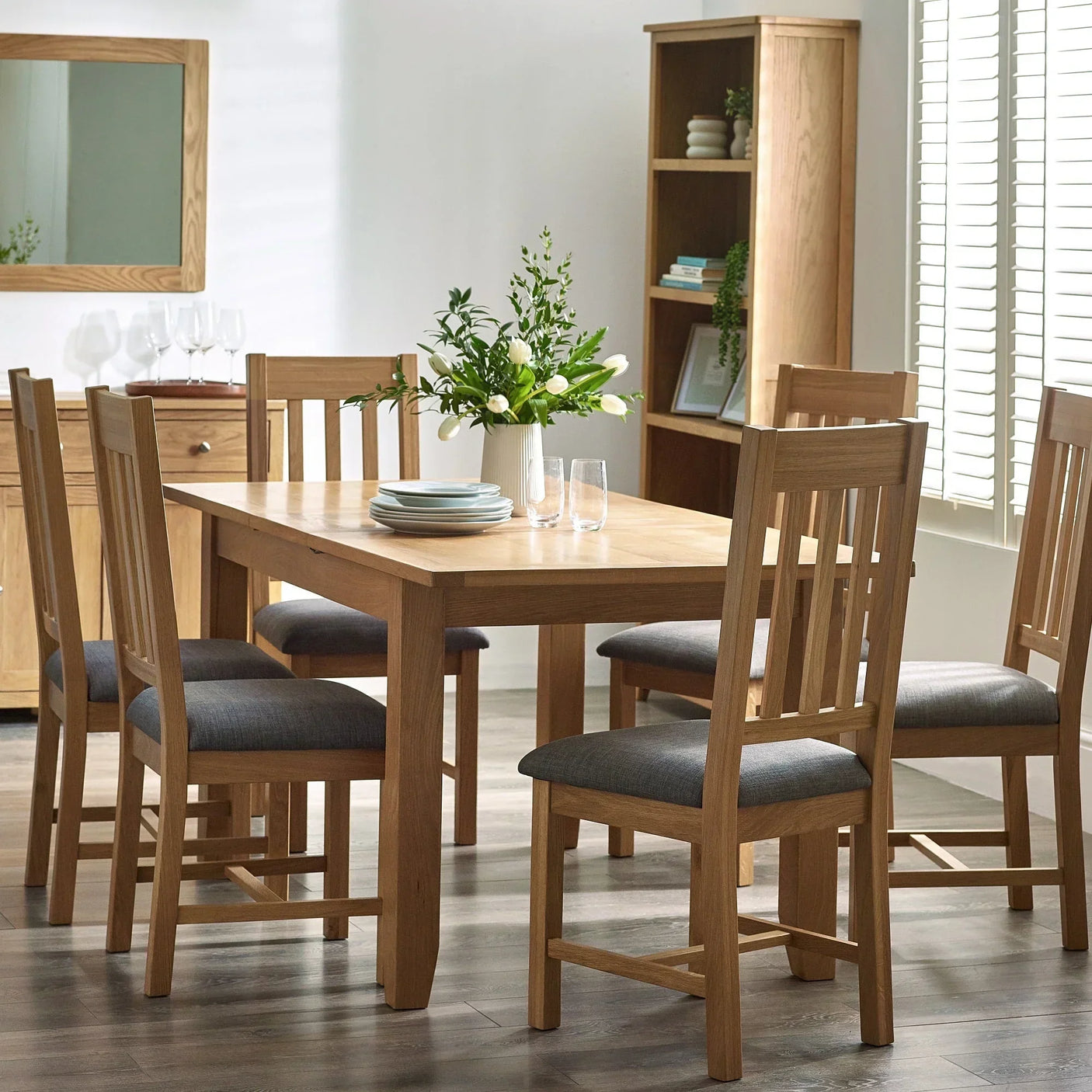 Oak Mallory dining chair with grey padded seat at wooden dining table in bright room