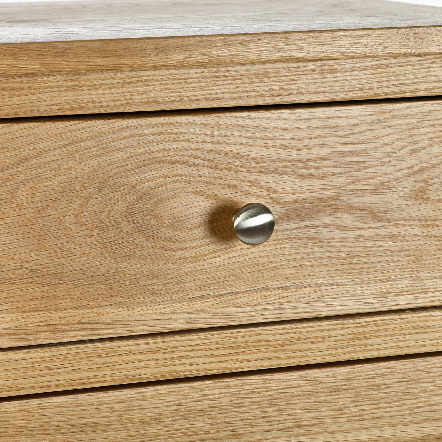 Close-up of oak bedside table drawer with brushed metal knob handle