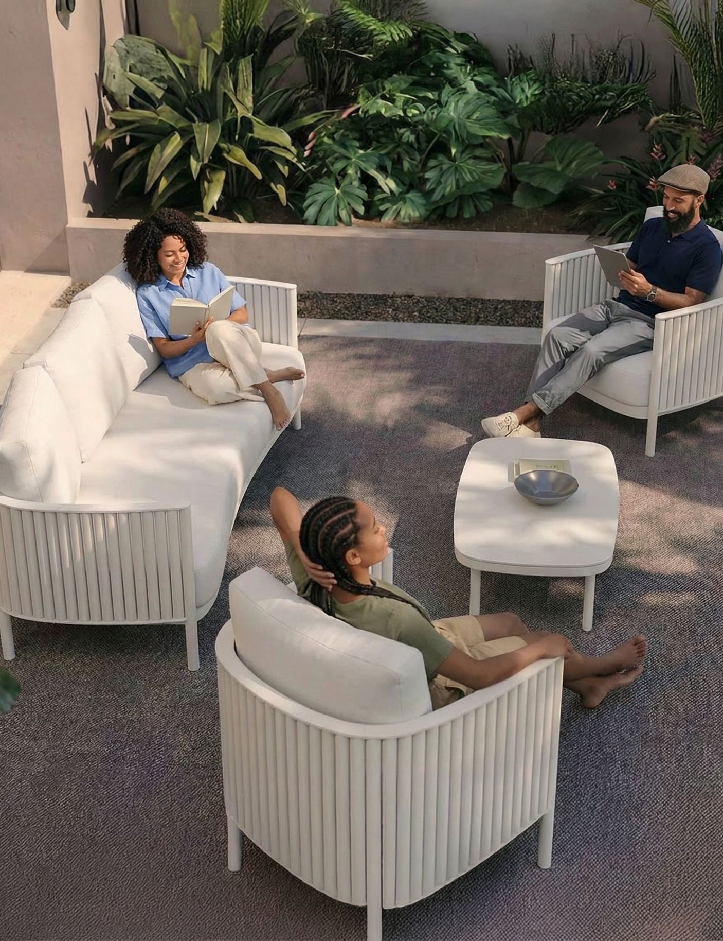 Image of White 5 seater outdoor lounging set with 3 people relaxing and reading