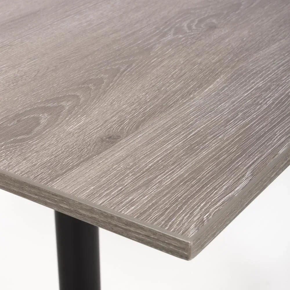 Close up of grey wood dining table top with visible grain and black metal leg