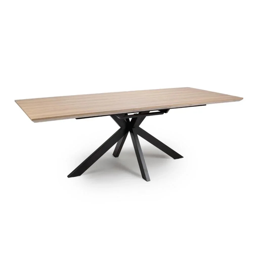 Rectangular dining table with light wood top and black metal star-shaped base, side view