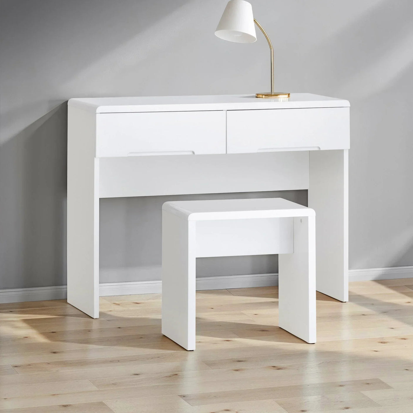 White dressing table with two drawers and matching stool on wooden floor