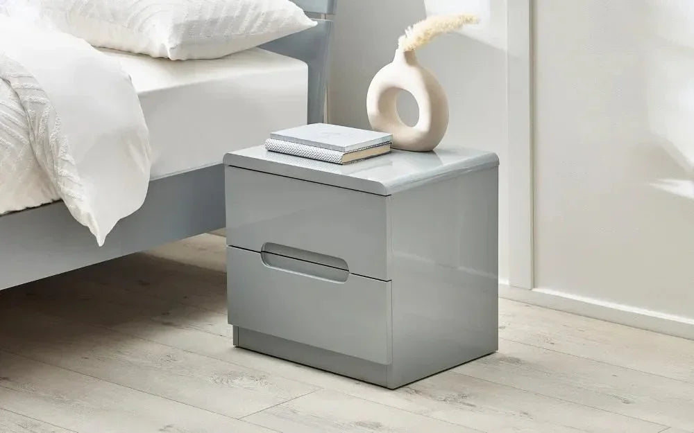 Grey bedside table with two drawers and books next to modern bed
