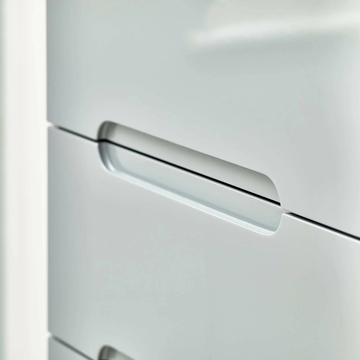 Grey narrow chest of drawers with integrated handle detail, modern bedroom furniture closeup