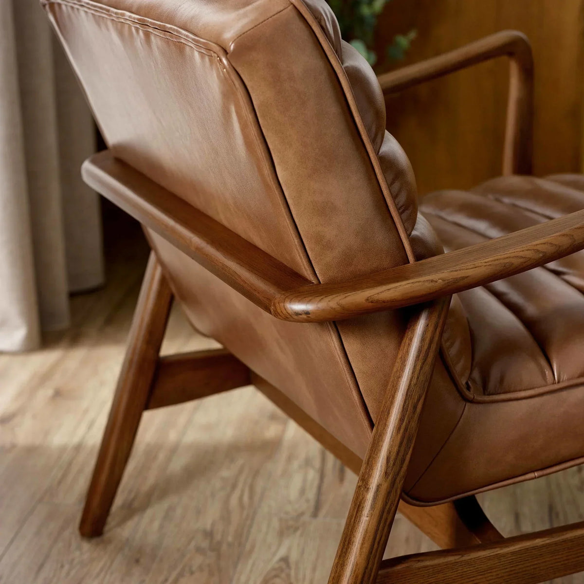 Brown leather armchair with wooden frame on oak flooring