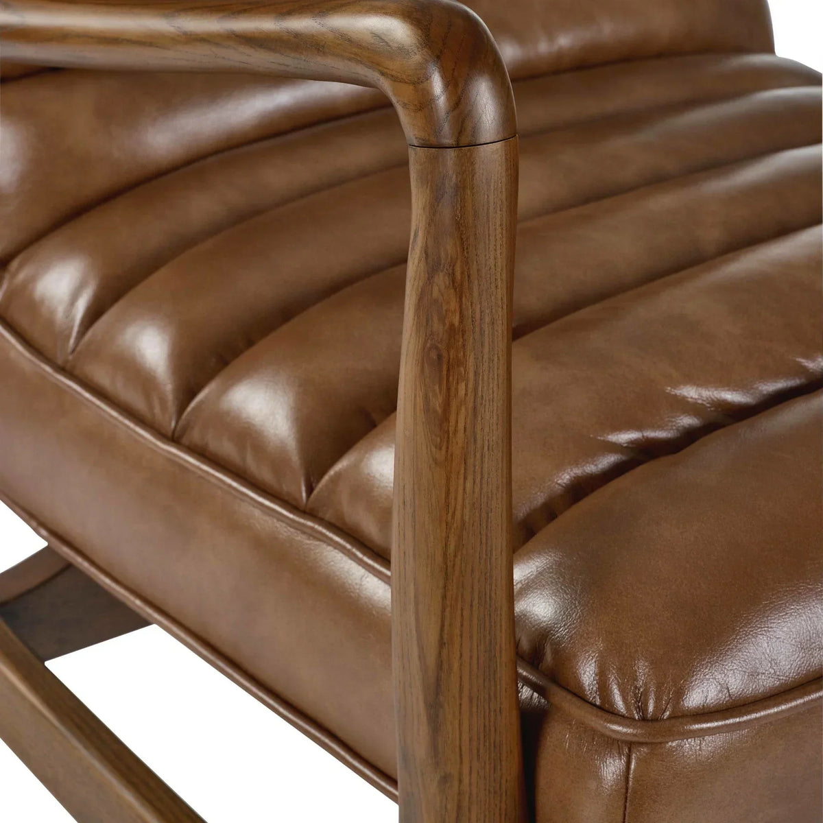 Close view of brown leather armchair with wooden armrest and stitched seat detailing