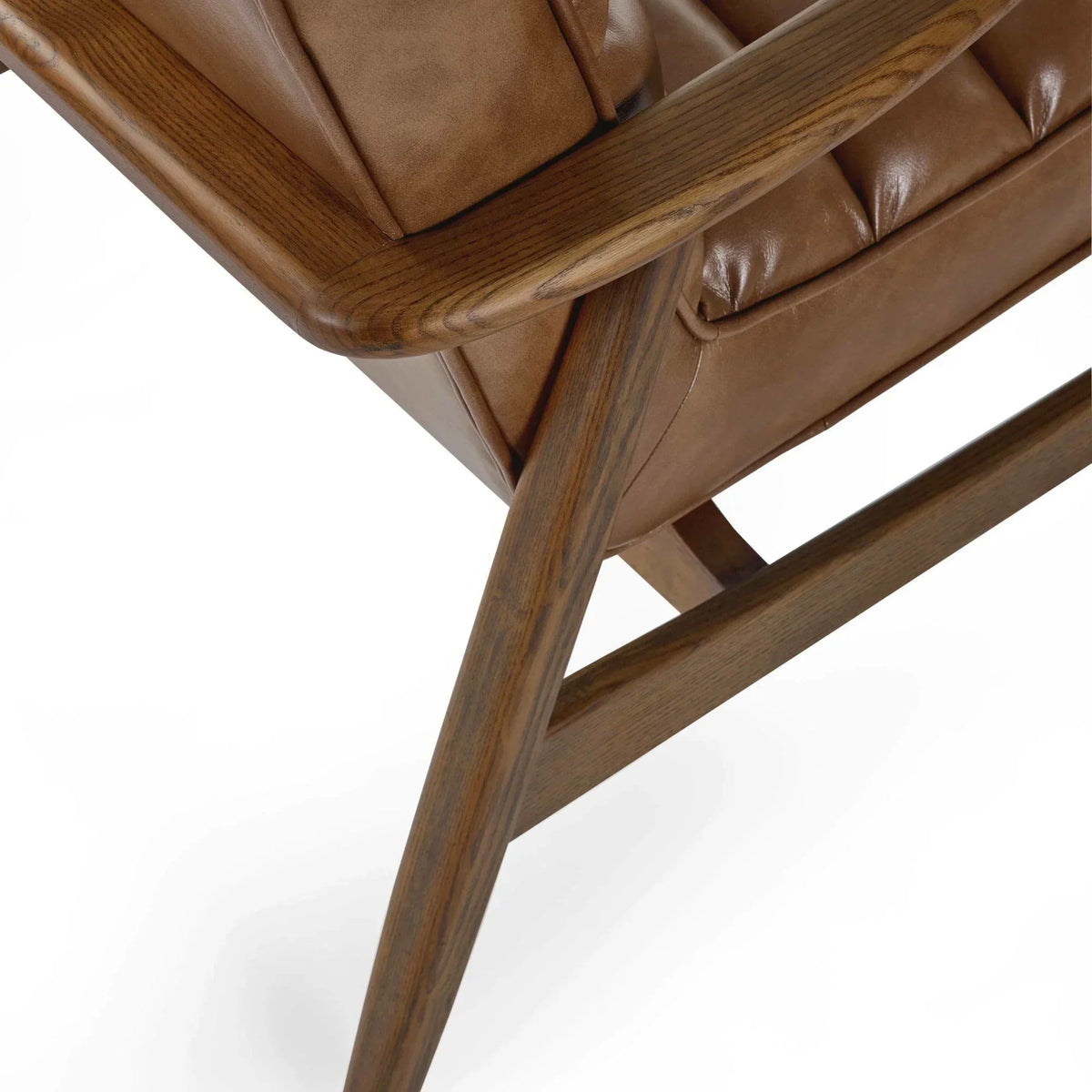 Close-up of brown leather armchair with tufted cushion and wooden armrest detail