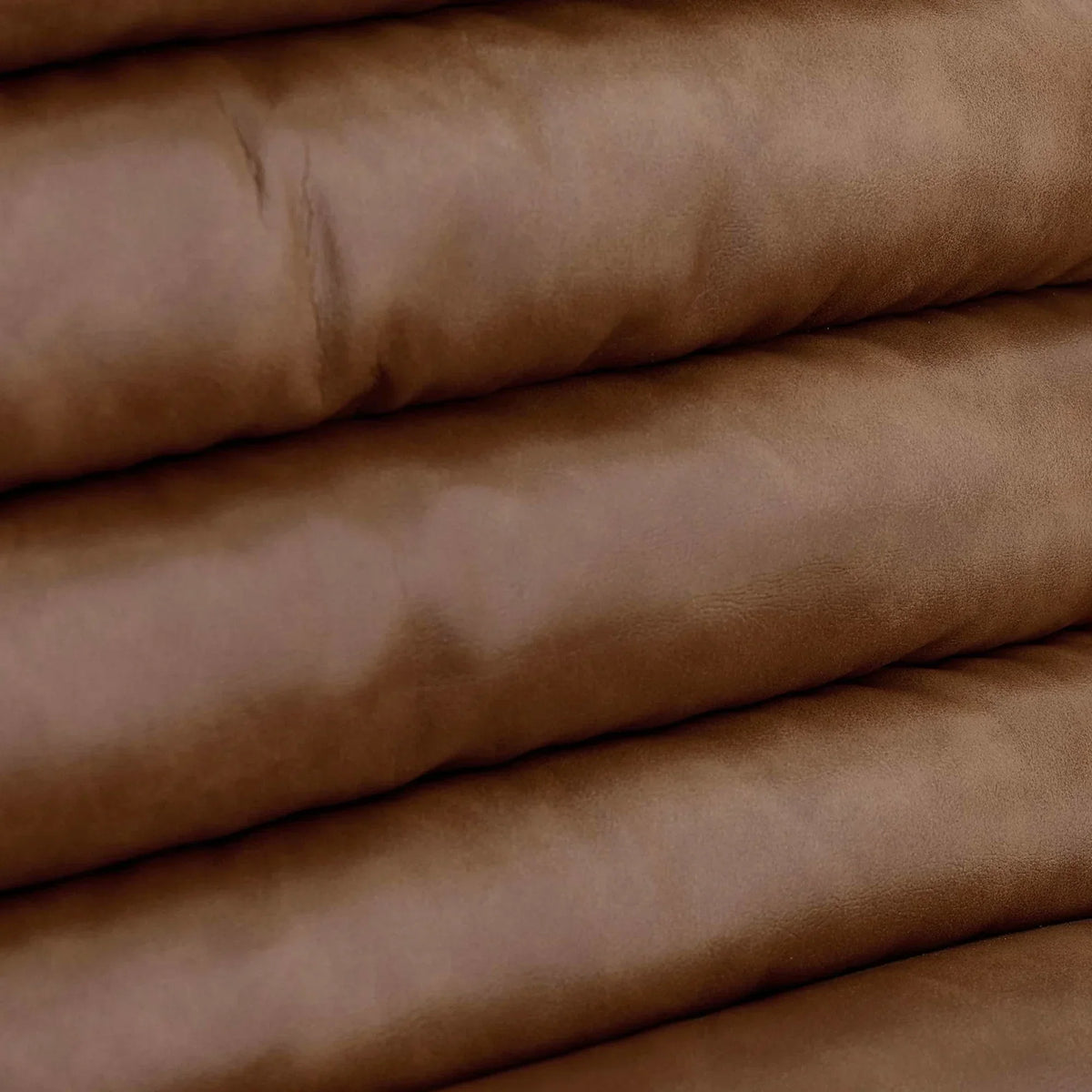 Close-up brown leather sofa cushion detailing and soft upholstery texture