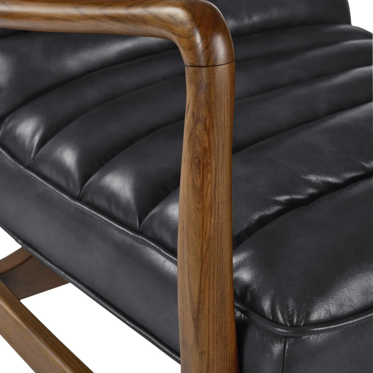 Black leather armchair with curved wooden armrest and stitched seat detail