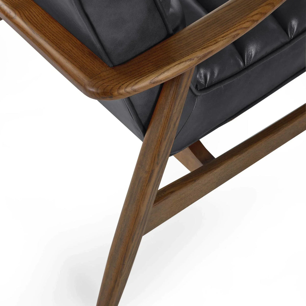 Dark wood armchair frame with black leather cushion, close-up of angled leg and stitching